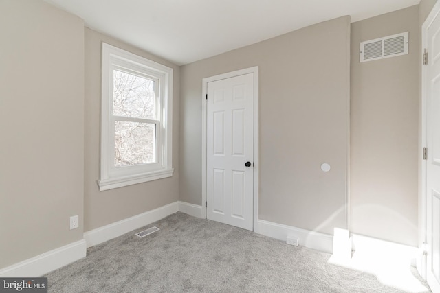 spare room with visible vents, light carpet, and baseboards