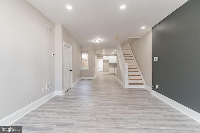 interior space featuring visible vents, light wood finished floors, baseboards, and stairs