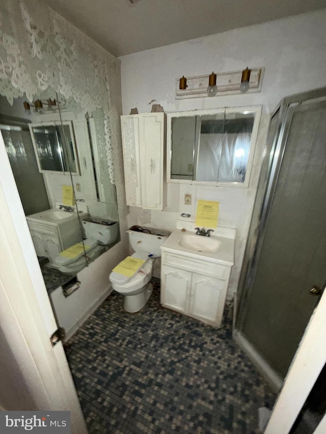 bathroom featuring toilet, vanity, and a shower with shower door