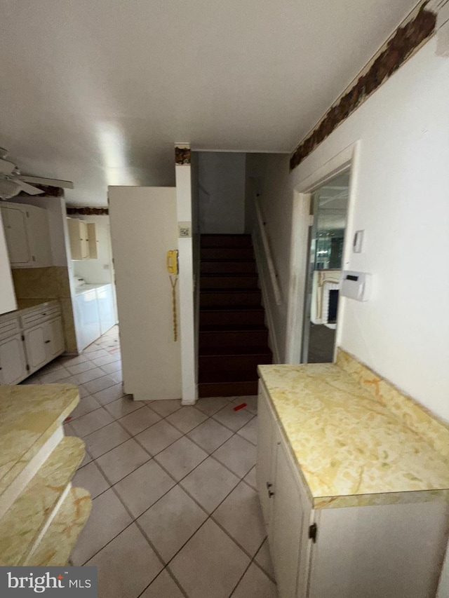 kitchen featuring light tile patterned flooring, ceiling fan, white cabinetry, and washer / dryer