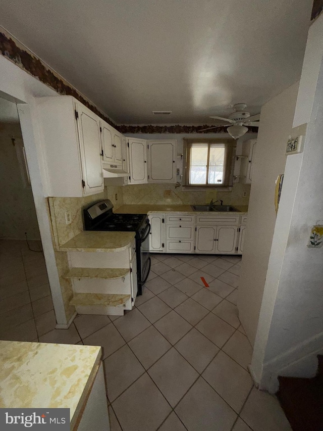 kitchen with white cabinets, light tile patterned floors, ceiling fan, and gas range