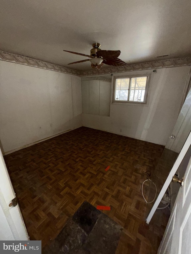 unfurnished room with ceiling fan and dark parquet flooring