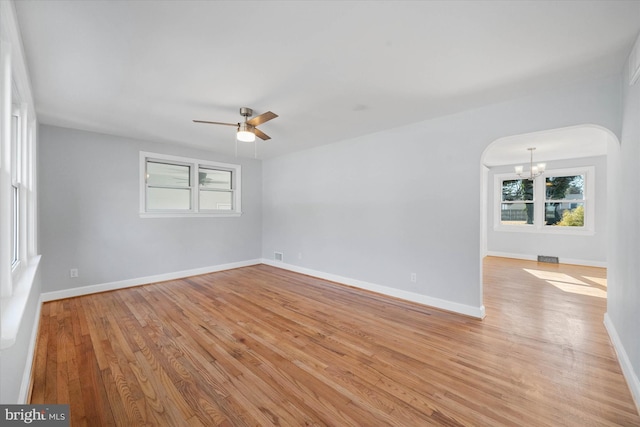 unfurnished room featuring ceiling fan with notable chandelier and light hardwood / wood-style flooring