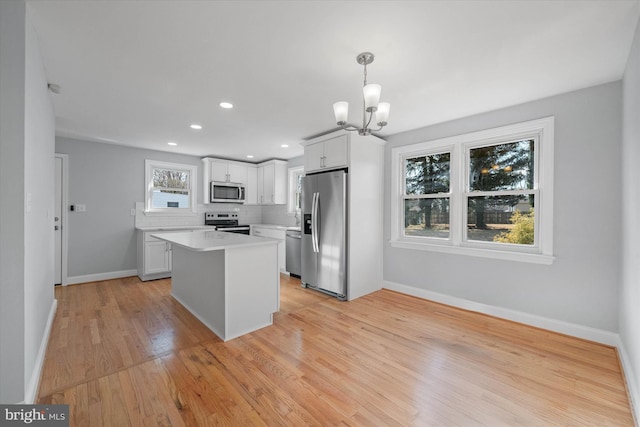 kitchen featuring tasteful backsplash, a center island, hanging light fixtures, appliances with stainless steel finishes, and white cabinets