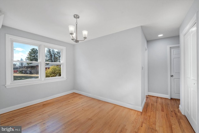 empty room with a chandelier and light wood-type flooring