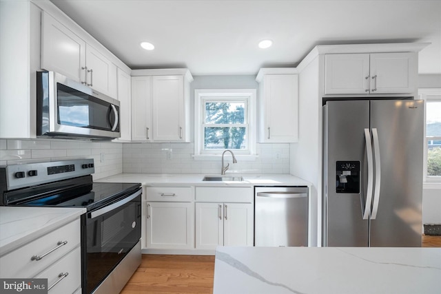 kitchen with light stone counters, sink, white cabinets, and appliances with stainless steel finishes