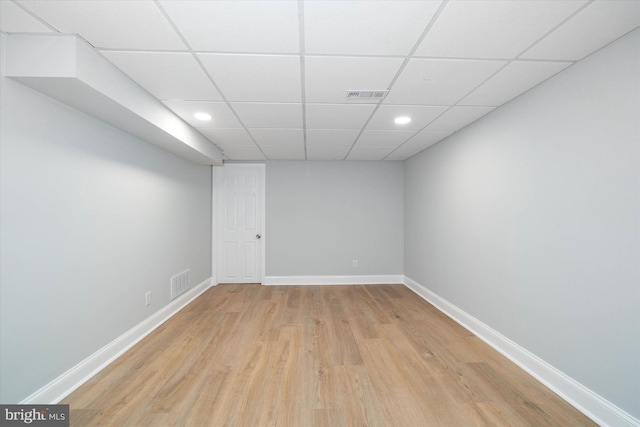 unfurnished room with a drop ceiling and light wood-type flooring