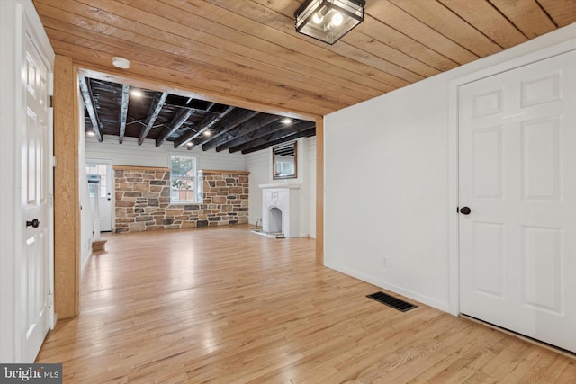 interior space with a stone fireplace, wooden ceiling, and light wood-type flooring