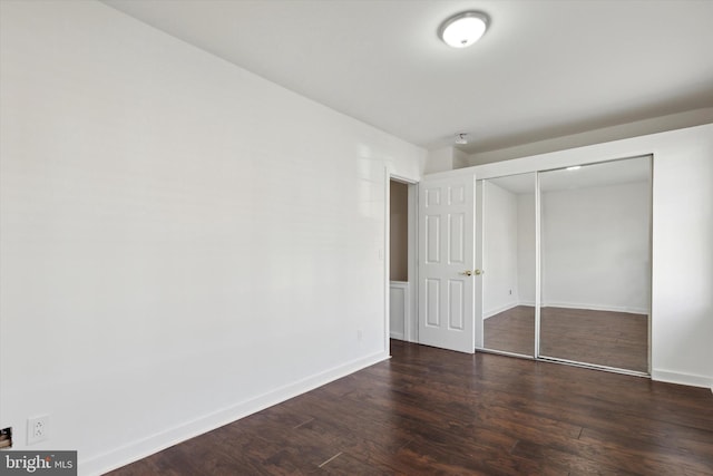 unfurnished bedroom with dark wood-type flooring and a closet