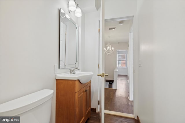 bathroom with wood-type flooring, vanity, and toilet