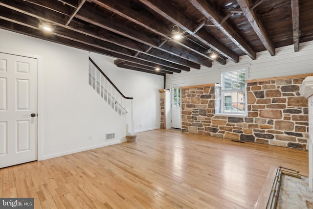 unfurnished living room with beamed ceiling and light wood-type flooring