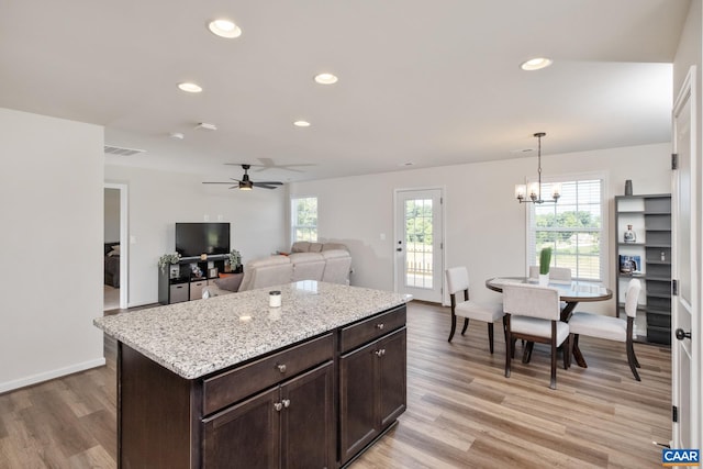 kitchen with pendant lighting, a center island, dark brown cabinets, and light wood-type flooring