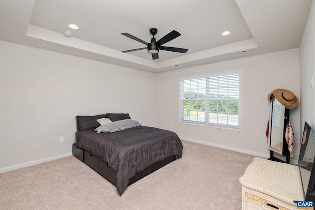 carpeted bedroom with ceiling fan and a raised ceiling