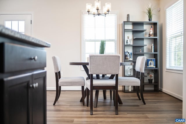 dining area with hardwood / wood-style floors and a notable chandelier