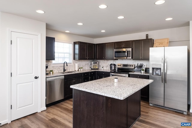 kitchen featuring sink, a center island, dark brown cabinets, light hardwood / wood-style flooring, and stainless steel appliances