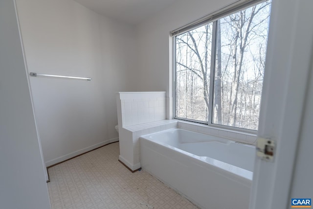 bathroom with a healthy amount of sunlight, a washtub, and toilet