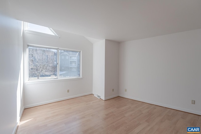 unfurnished room featuring vaulted ceiling and light hardwood / wood-style floors