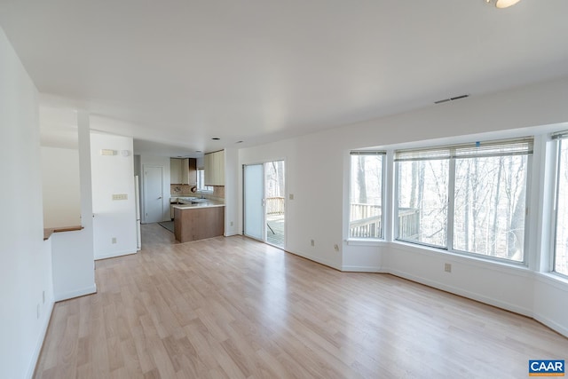 unfurnished living room with a healthy amount of sunlight and light hardwood / wood-style flooring