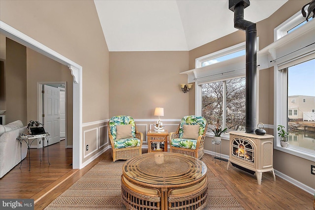 living area with dark hardwood / wood-style flooring, a high ceiling, and a wood stove