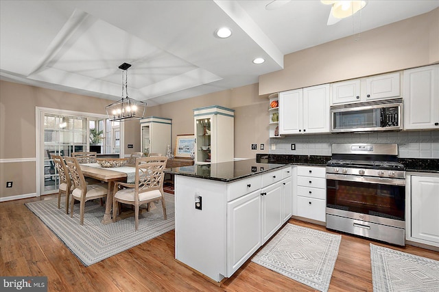 kitchen featuring stainless steel appliances, a raised ceiling, pendant lighting, and white cabinets