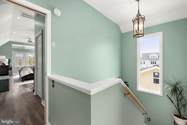 corridor featuring vaulted ceiling, wood-type flooring, and an inviting chandelier