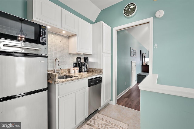 kitchen featuring sink, light stone counters, tasteful backsplash, appliances with stainless steel finishes, and white cabinets