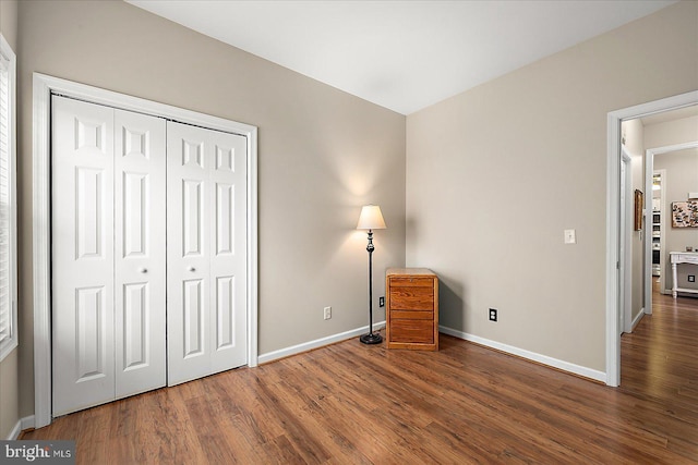 unfurnished bedroom with dark wood-type flooring and a closet