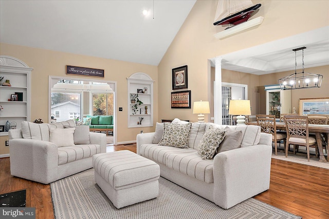 living room featuring decorative columns, wood-type flooring, and high vaulted ceiling