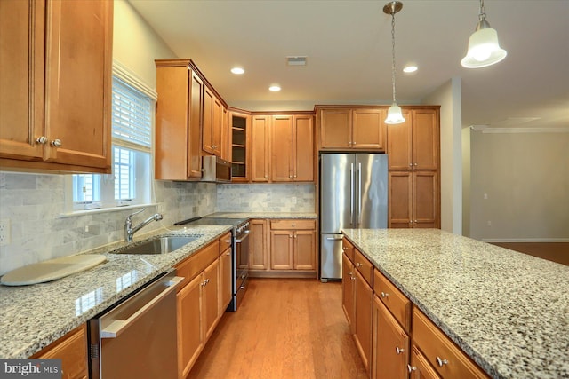 kitchen featuring stainless steel appliances, decorative light fixtures, light stone countertops, and sink