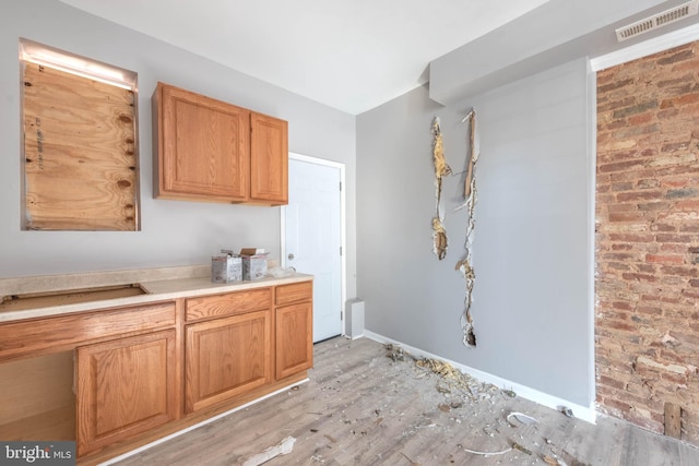 kitchen with brick wall and light hardwood / wood-style floors