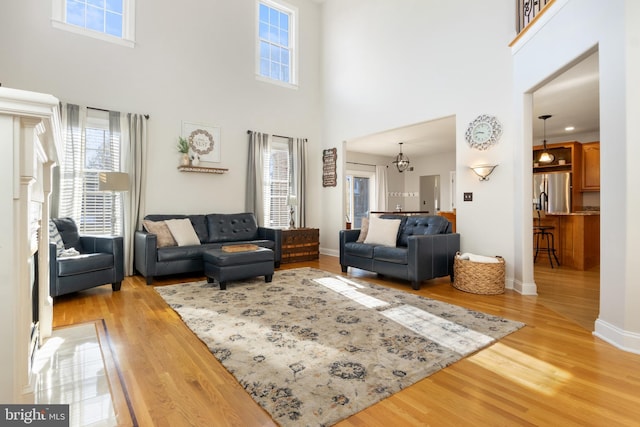 living room with an inviting chandelier, light hardwood / wood-style flooring, and a high ceiling