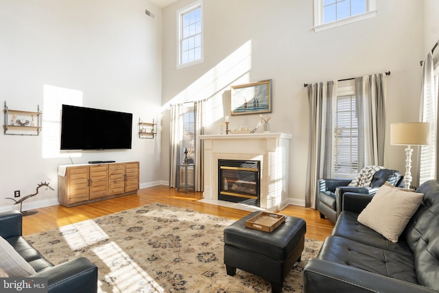 living room with plenty of natural light, a towering ceiling, and light wood-type flooring