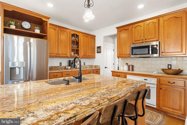 kitchen featuring decorative light fixtures, sink, backsplash, light stone counters, and stainless steel appliances