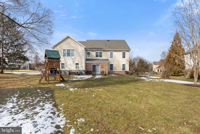 snow covered back of property featuring a playground and a lawn