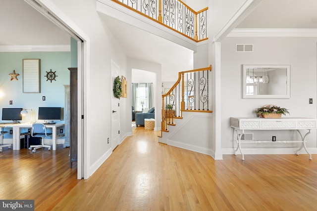 entrance foyer featuring a high ceiling, crown molding, and light wood-type flooring