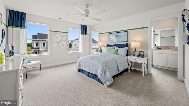 carpeted bedroom with ensuite bathroom, sink, and ceiling fan