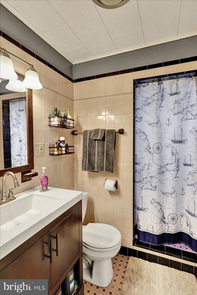 bathroom featuring toilet, tile walls, vanity, and walk in shower