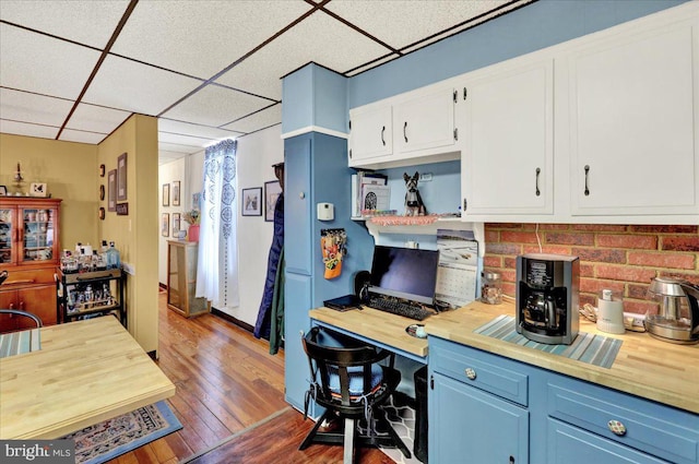 kitchen featuring a drop ceiling, wood-type flooring, blue cabinetry, and white cabinets