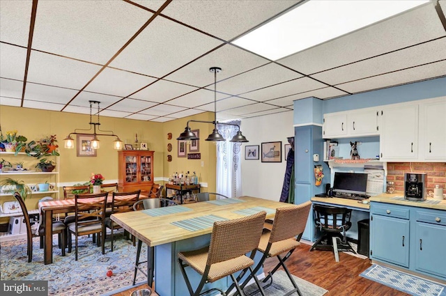 dining space featuring dark wood-type flooring and a drop ceiling