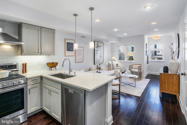 kitchen with sink, gray cabinetry, light stone counters, appliances with stainless steel finishes, and kitchen peninsula