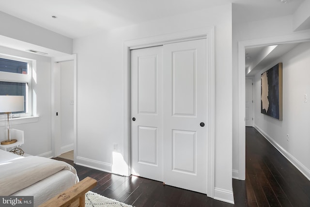 bedroom with dark hardwood / wood-style flooring and a closet