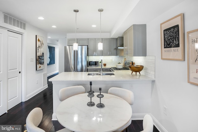 kitchen with gray cabinets, pendant lighting, sink, kitchen peninsula, and stainless steel appliances