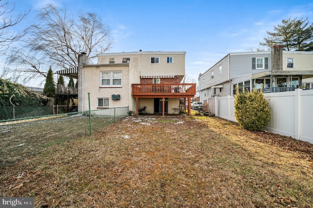 back of house with a wooden deck and a lawn