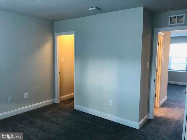 unfurnished room featuring dark colored carpet