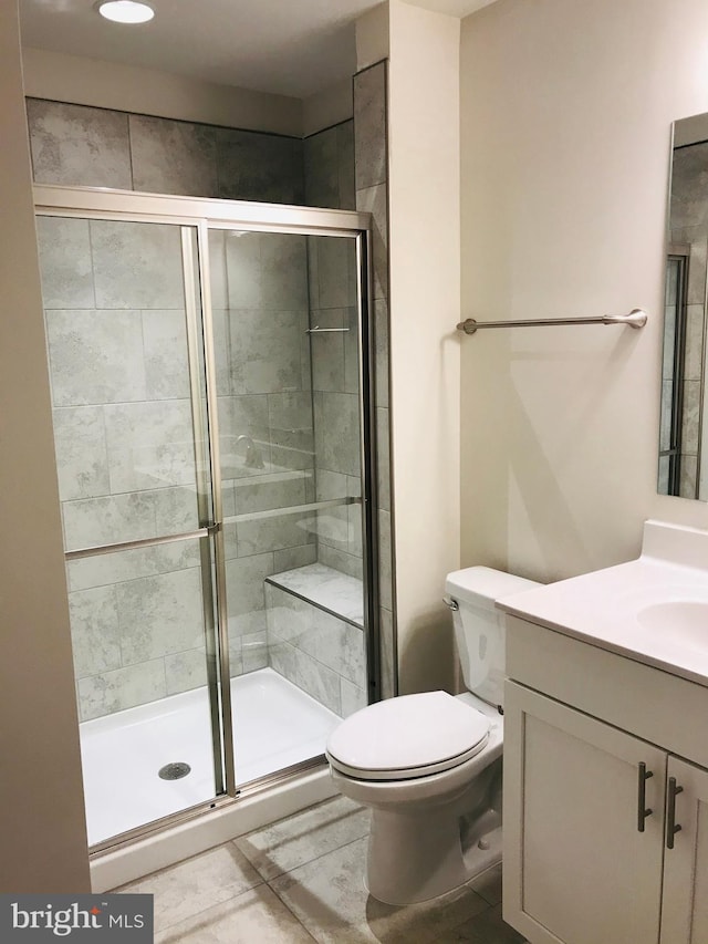 bathroom featuring vanity, toilet, and a shower with shower door