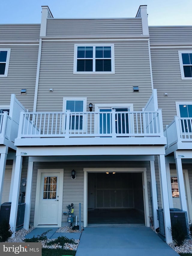 back of house featuring a garage, central AC, and a balcony