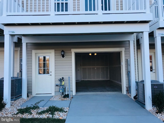 view of exterior entry with a balcony and central AC unit