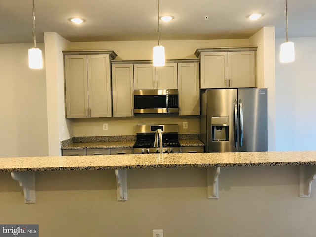 kitchen with stainless steel appliances, light stone counters, a kitchen bar, and decorative light fixtures