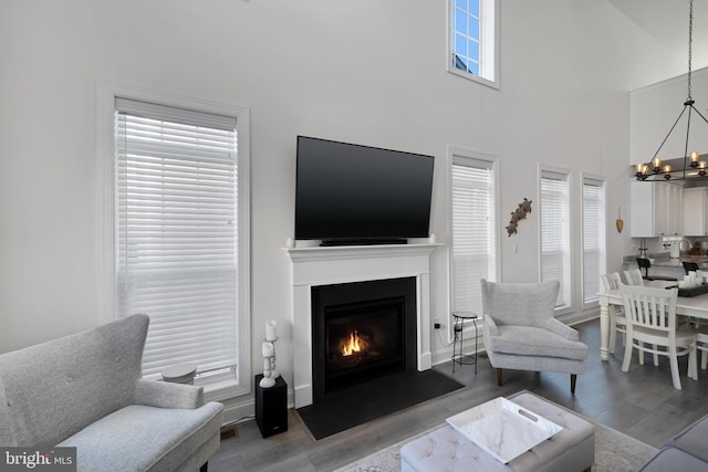 living room featuring a high ceiling, wood-type flooring, and a notable chandelier