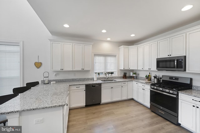 kitchen featuring sink, light hardwood / wood-style flooring, kitchen peninsula, stainless steel appliances, and white cabinets